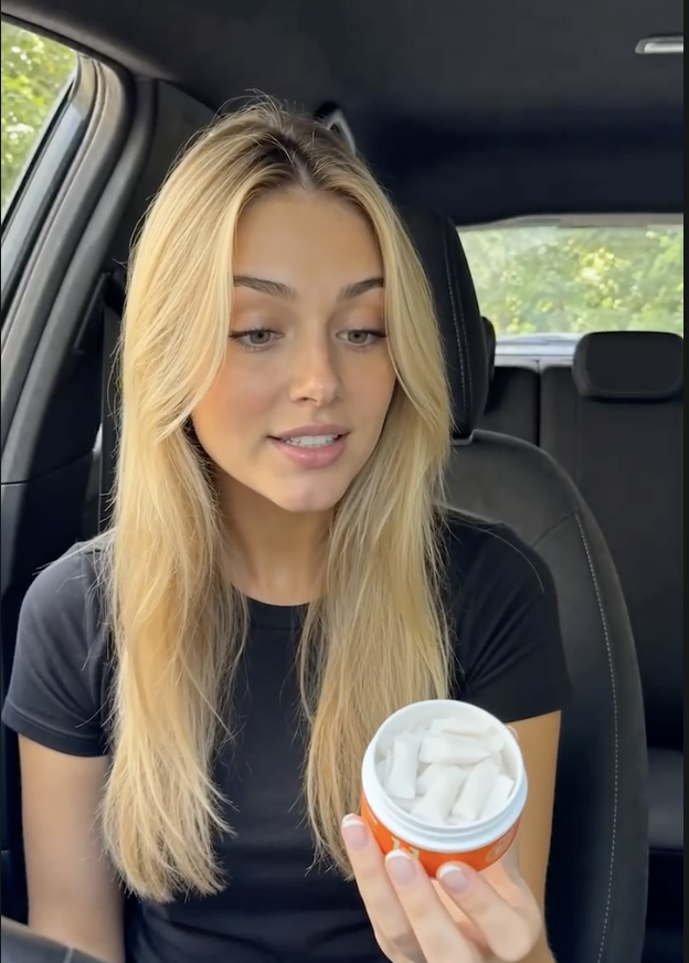 Person showing an open ABSORBED tin with white pouches