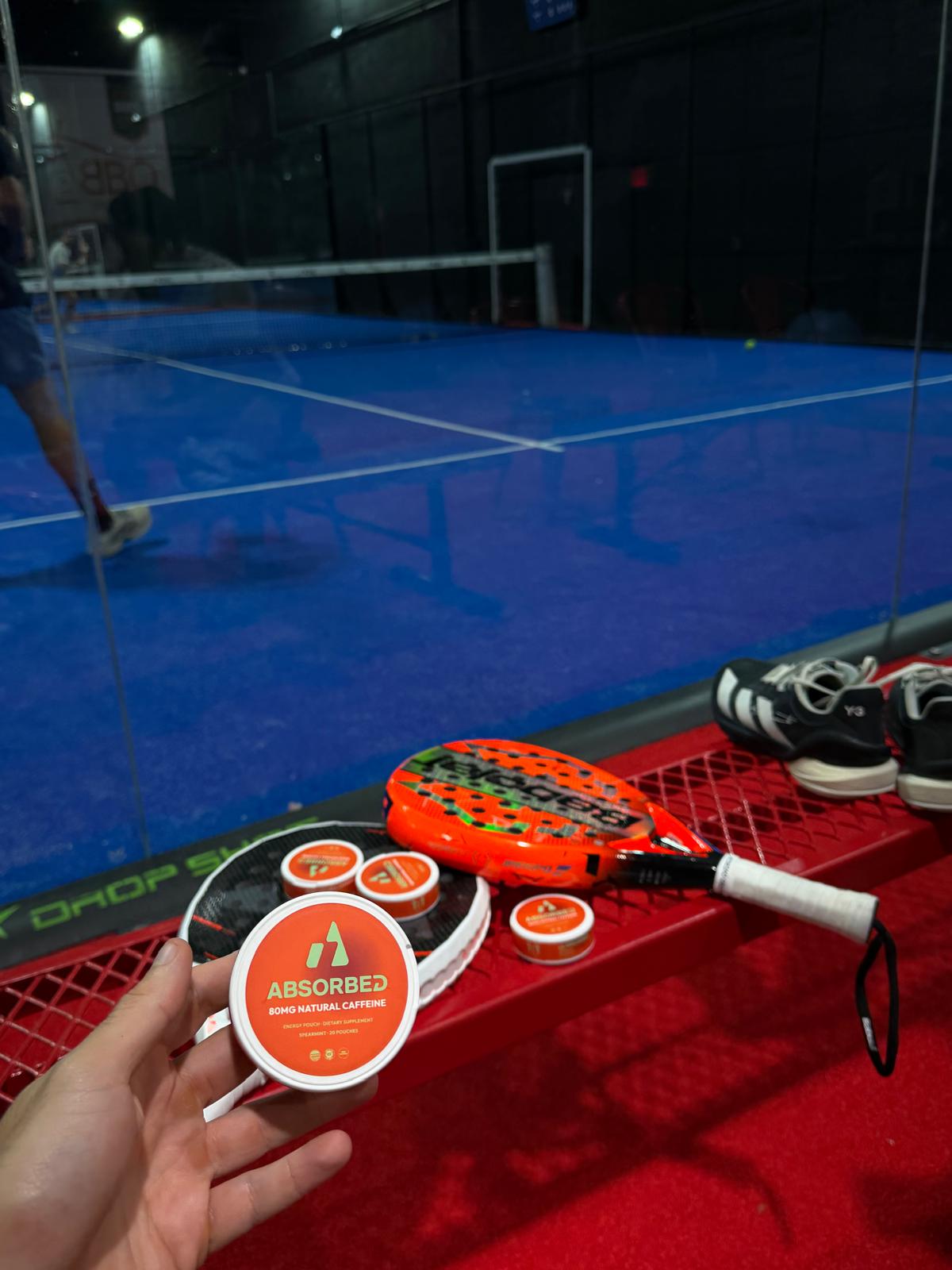 ABSORBED tins beside padel rackets at the court
